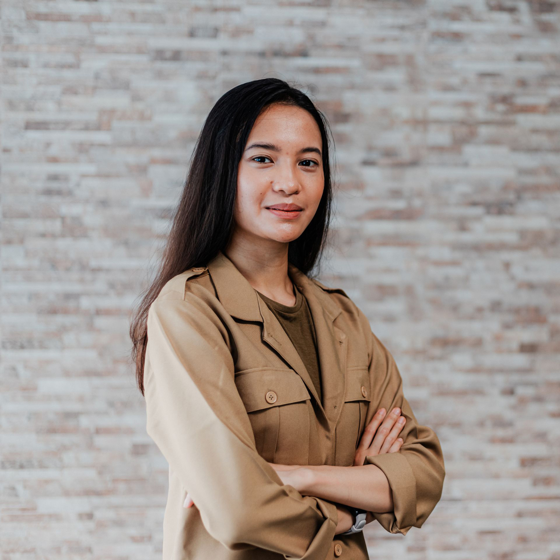 A young woman standing in front of a brick wall