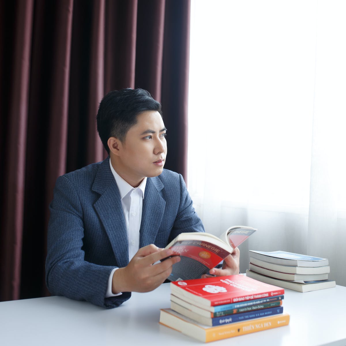 Pensive young man in a suit sitting at a table with books